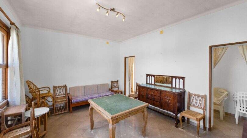 Wohnzimmer der Villa in Cala Figuera mit antikem Holzmöbeln, grünem Spieltisch und Rattanstühlen