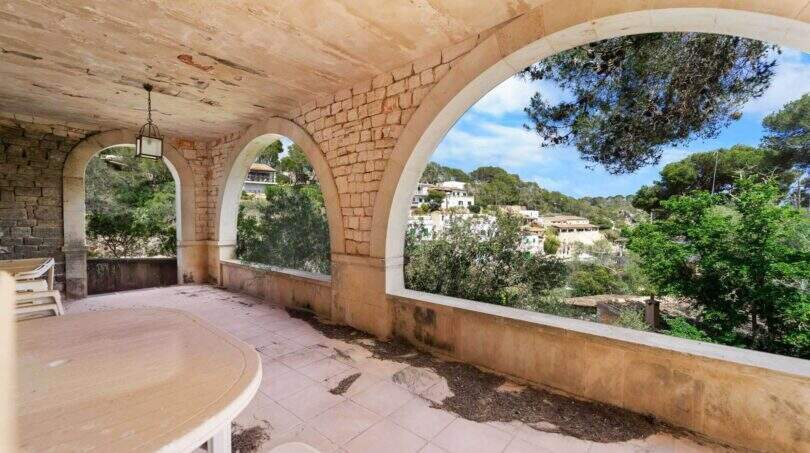 Überdachte Terrasse mit Steinbögen und Blick auf Cala Figueras Dorflandschaft und Pinien