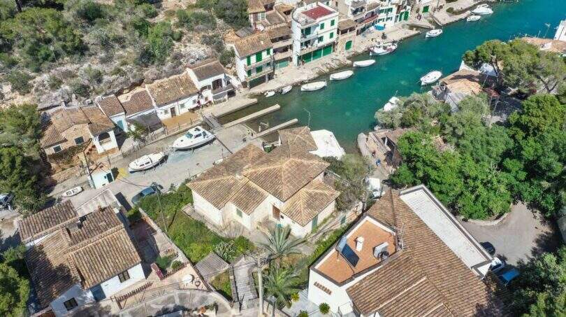 Luftaufnahme des malerischen Hafens von Cala Figuera mit türkisblauem Wasser, Booten und mediterranen Häusern in erster Meereslinie.