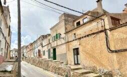 Enge Dorfstraße in Felanitx mit historischen Steinhäusern, grünen Fensterläden und charakteristischer mallorquinischer Architektur.