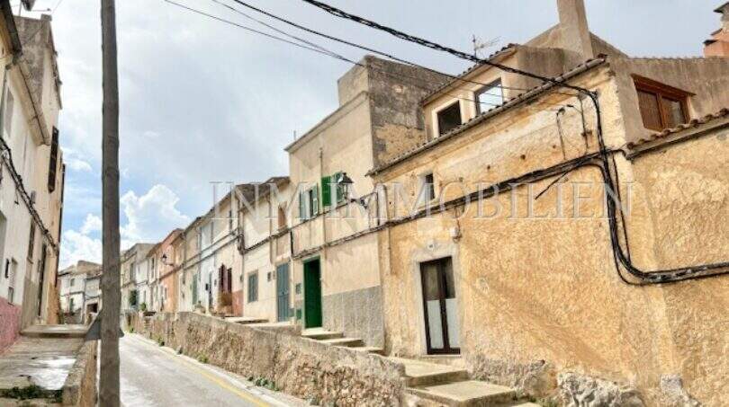 Enge Dorfstraße in Felanitx mit historischen Steinhäusern, grünen Fensterläden und charakteristischer mallorquinischer Architektur.