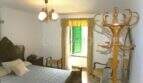 Schlafzimmer mit Doppelbett, antikem Holzmöbel, Garderobe und Fenster mit grünen Holzläden in Felanitx