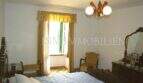 Schlafzimmer mit Doppelbett, goldfarbenen Vorhängen, Holzmöbeln und Fenster zum Patio im Dorfhaus Felanitx