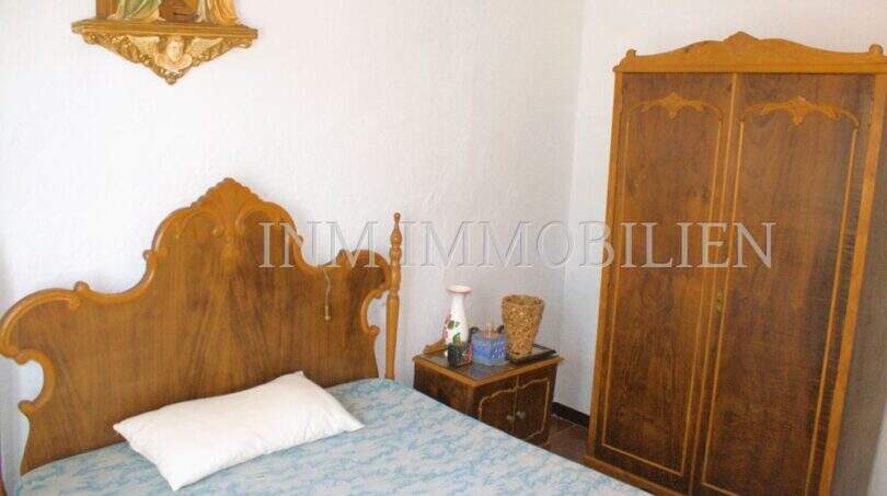 Schlafzimmer mit antikem Holzbett, passendem Kleiderschrank und religiösem Wandschmuck im Dorfhaus Felanitx