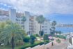 Außenansicht Apartment Palmanova: Wohnanlage mit Palmen, gepflegtem Garten und Meerblick auf den Hafen.
