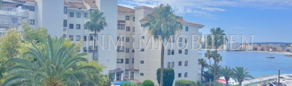 Außenansicht Apartment Palmanova: Wohnanlage mit Palmen, gepflegtem Garten und Meerblick auf den Hafen.