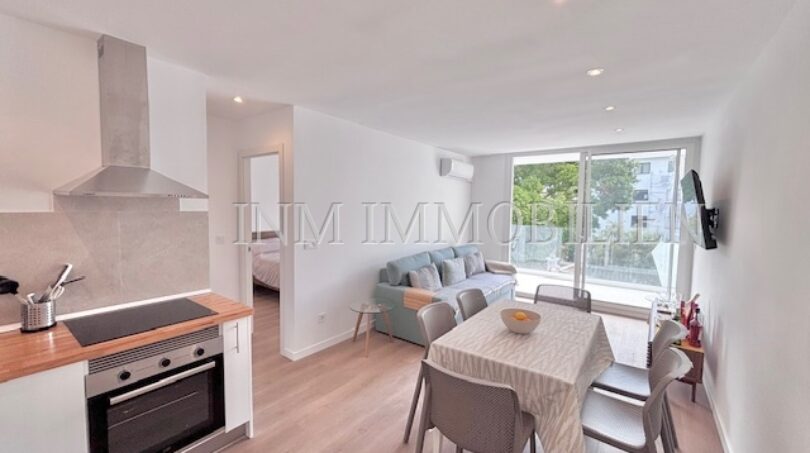 Helles Wohn-Esszimmer mit offener Küche, Balkon und modernem Inventar im Apartment Palmanova