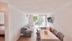 Helles Wohnzimmer mit grauem Sofa, Esstisch und Balkon in renoviertem Apartment Palmanova