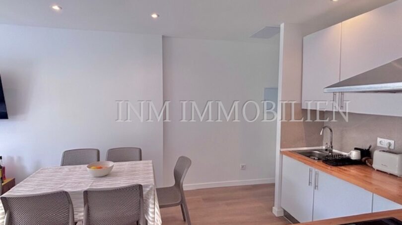 Helle Wohnküche mit weißen Einbauschränken, Esstisch für 4 Personen und modernem Holzboden im Apartment Palmanova