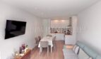 Helles Wohnzimmer mit Sofa, Esstisch und offener Küche in renoviertem Apartment in Palmanova