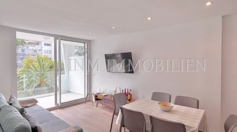 Helles Wohnzimmer mit Esstisch, Sofa, TV und Balkon mit Palmenblick in Palmanova-Apartment