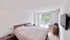 Helles Schlafzimmer mit Doppelbett, Holzmöbeln, Wand-TV und Zugang zur Terrasse in Palmanova-Apartment