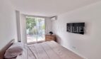 Helles Schlafzimmer mit Doppelbett, Wandmontiertem TV, Klimaanlage und Balkonzugang in Palmanova-Apartment