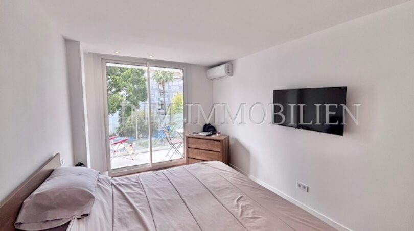 Helles Schlafzimmer mit Doppelbett, Wandmontiertem TV, Klimaanlage und Balkonzugang in Palmanova-Apartment