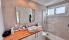 Modernes Badezimmer mit Waschtisch, Glasdusche und Waschmaschine im Apartment Palmanova