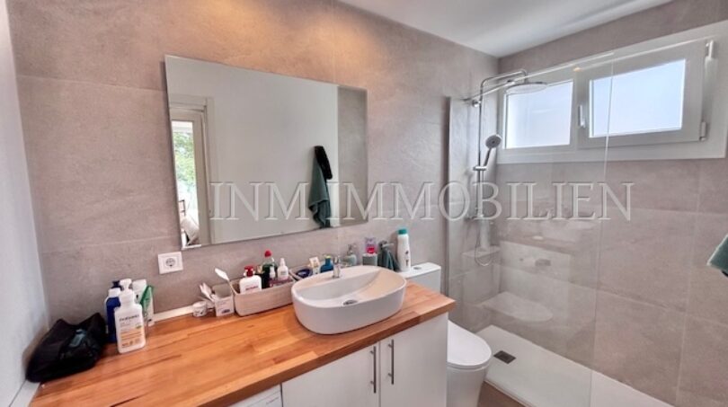 Modernes Badezimmer mit Waschtisch, Glasdusche und Waschmaschine im Apartment Palmanova