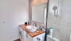 Modernes Badezimmer mit Waschtisch, Spiegel, Dusche und Waschmaschine im Apartment Palmanova