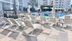 Poolbereich mit weißen Liegestühlen und Sonnenschirmen im Apartment-Komplex Palmanova, Palma Nova