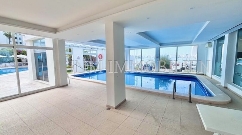 Überdachter Innenpool mit Glasfronten und Blick auf Außenpool im Apartment-Komplex in Palmanova