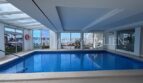 Überdachter Innenpool mit Panoramafenstern und Meerblick im Apartmentkomplex in Palmanova