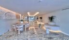 Eleganter Wohn-Essbereich mit Marmorboden, Designermöbeln und indirekter Beleuchtung in Palmanova-Apartment