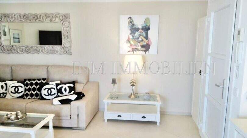 Helles Wohnzimmer im Luxus-Penthouse Playa de Palma mit beigem Sofa, weißen Möbeln und stilvoller Dekoration.