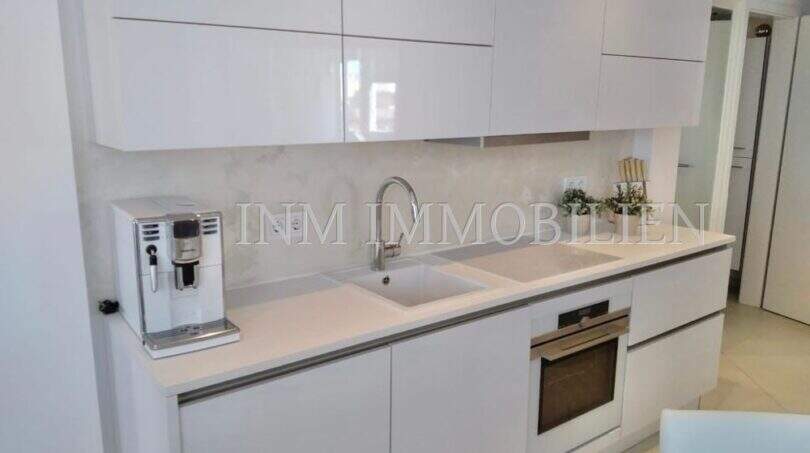 Moderne weiße Hochglanzküche mit Einbauofen, Doppelspüle und Kaffeemaschine im Luxus-Penthouse Playa de Palma