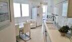 Moderne, weiße Küche mit Marmoroptik-Rückwand und offener Wohnbereich im Luxus-Penthouse Playa de Palma