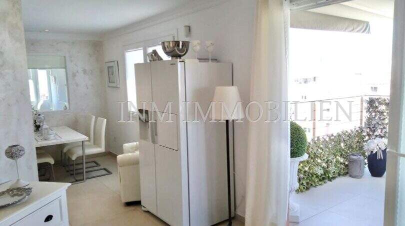 Helles Wohnzimmer mit Terrassenzugang, weißer Einrichtung und Blick auf begrünte Balkonterrasse im Penthouse Palma.