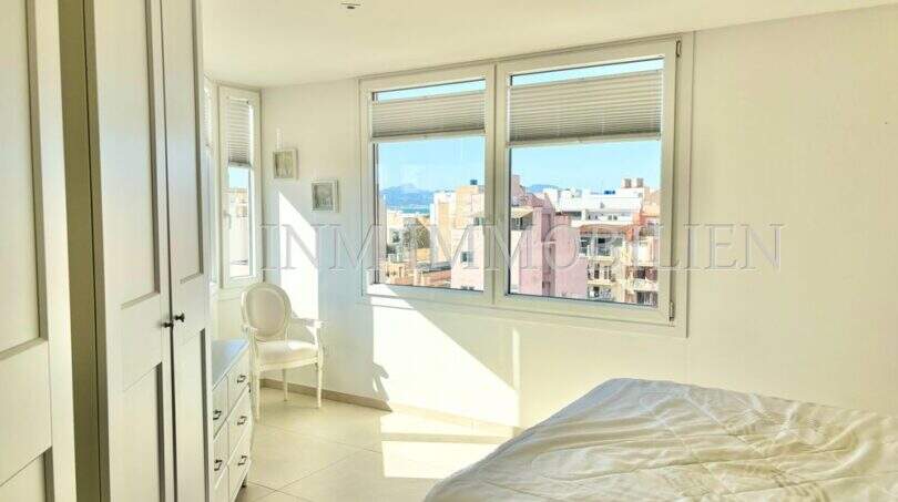 Helles Schlafzimmer im Penthouse mit großen Fenstern und Blick über Palma de Mallorca zum Meer.