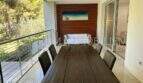 Überdachte Terrasse mit Holztisch, 6 Stühlen und Blick in Grünanlage, moderne Luxuswohnung Bendinat