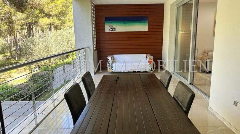 Überdachte Terrasse mit Holztisch, 6 Stühlen und Blick in Grünanlage, moderne Luxuswohnung Bendinat