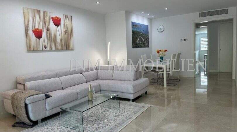 Helles Wohnzimmer mit grauem Ecksofa, Marmorboden und Esstisch in moderner Luxuswohnung in Bendinat.