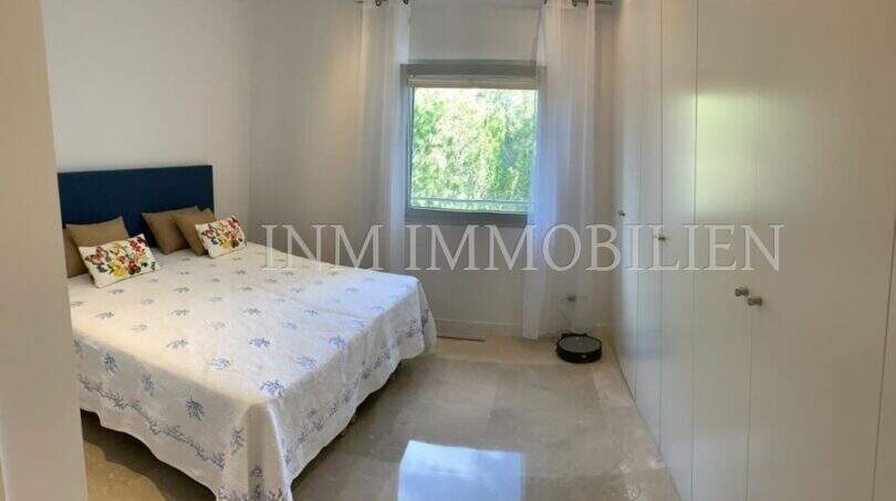 Helles Schlafzimmer der Luxuswohnung in Bendinat mit Doppelbett, Einbauschrank und Marmorböden.