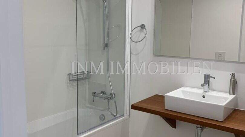 Modernes Badezimmer mit Badewanne, Dusche, Waschtisch auf Holzablage und Spiegel in Luxuswohnung Bendinat