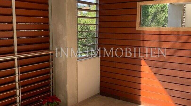 Überdachter Balkon mit Holzlamellen-Verkleidung, Marmorboden und Metallgeländer in moderner Luxuswohnung in Bendinat.