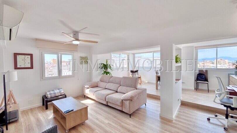 Helles Wohnzimmer mit Sofa, Deckenventilator und großen Fenstern mit Stadtblick in Can Pastilla, Palma