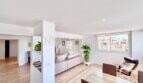 Helles Wohnzimmer mit Laminatboden, rosa Sofa, Ledersessel und großem Fenster in möblierter Wohnung Can Pastilla