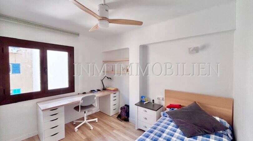 Helles Schlafzimmer mit Einzelbett, Schreibtisch, Deckenventilator und Parkettboden in Can Pastilla
