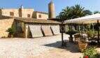 Rustikaler Innenhof mit Natursteinpflaster, Palmen, Windmühle und überdachter Terrasse in S'Aranjassa, Palma
