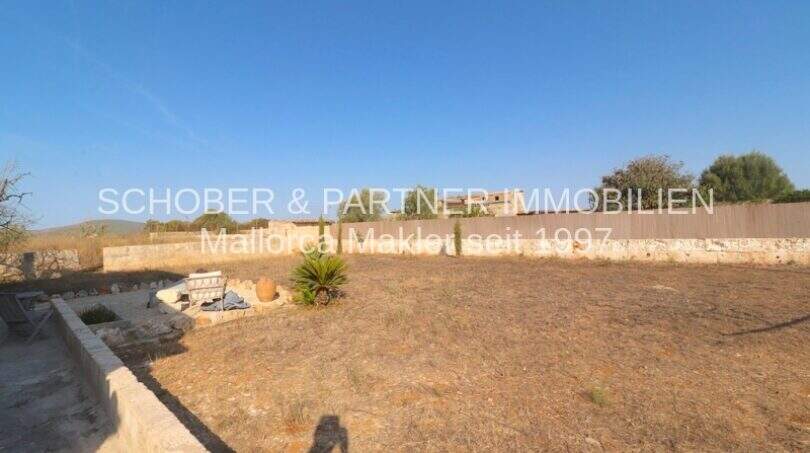 Weitläufiges Grundstück eines Landhauses in Portocristo mit trockenem Garten, Steinmauern und Bergblick.