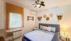 Helles Schlafzimmer mit Doppelbett, Klimaanlage, Deckenventilator und dekorativen Strohhüten in Cala Murada.