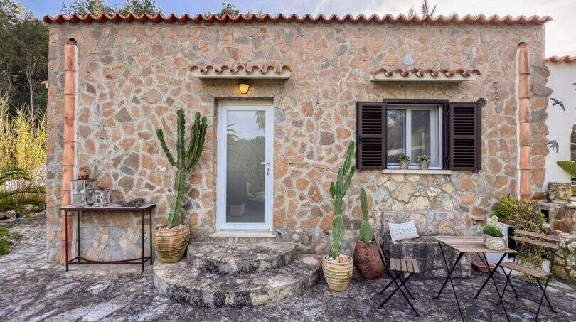 Rustikale Steinhaus-Fassade mit Kakteen, Holzläden und mediterranem Charme in Cala Murada