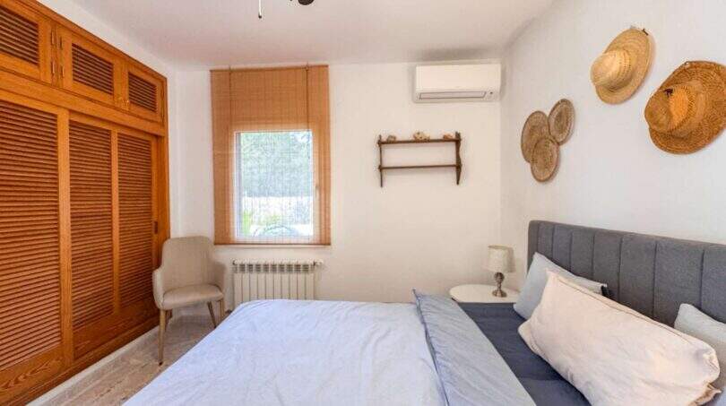 Helles Schlafzimmer mit Doppelbett, Holzschrank, Klimaanlage und Strohhut-Deko in Cala Murada
