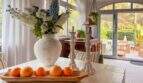 Helles Esszimmer mit Holztisch, weißer Vase, Kerzenständern und Meerblick-Terrasse in Cala Murada