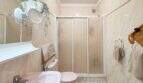 Helles Badezimmer mit Duschkabine, WC, Waschbecken und Pflanzendekor in der Strandwohnung Cala Murada