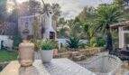 Mediterrane Terrasse mit Palmen, Agaven, Außenkamin und dekorativem Tisch nahe dem Strand in Cala Murada