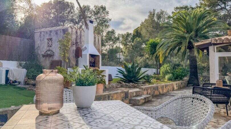 Mediterrane Terrasse mit Palmen, Agaven, Außenkamin und dekorativem Tisch nahe dem Strand in Cala Murada