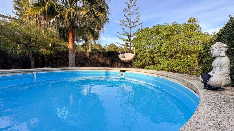 Runder Pool mit Palme, Hängesessel und Buddha-Statue im mediterranen Garten der Wohlfühloase in Cala Murada