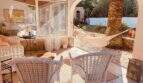 Überdachte Terrasse mit weißen Rattanmöbeln, Hängematte und Palme in Cala Murada